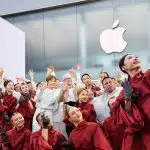 Group of performers taking a selfie outside an Apple Store during anniversary celebration.