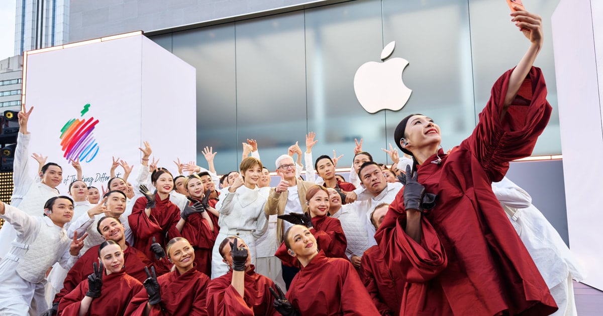 Group of performers taking a selfie outside an Apple Store during anniversary celebration.