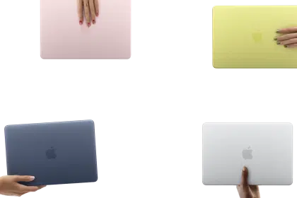 Four colourful MacBook laptops held by hands against a clean background.