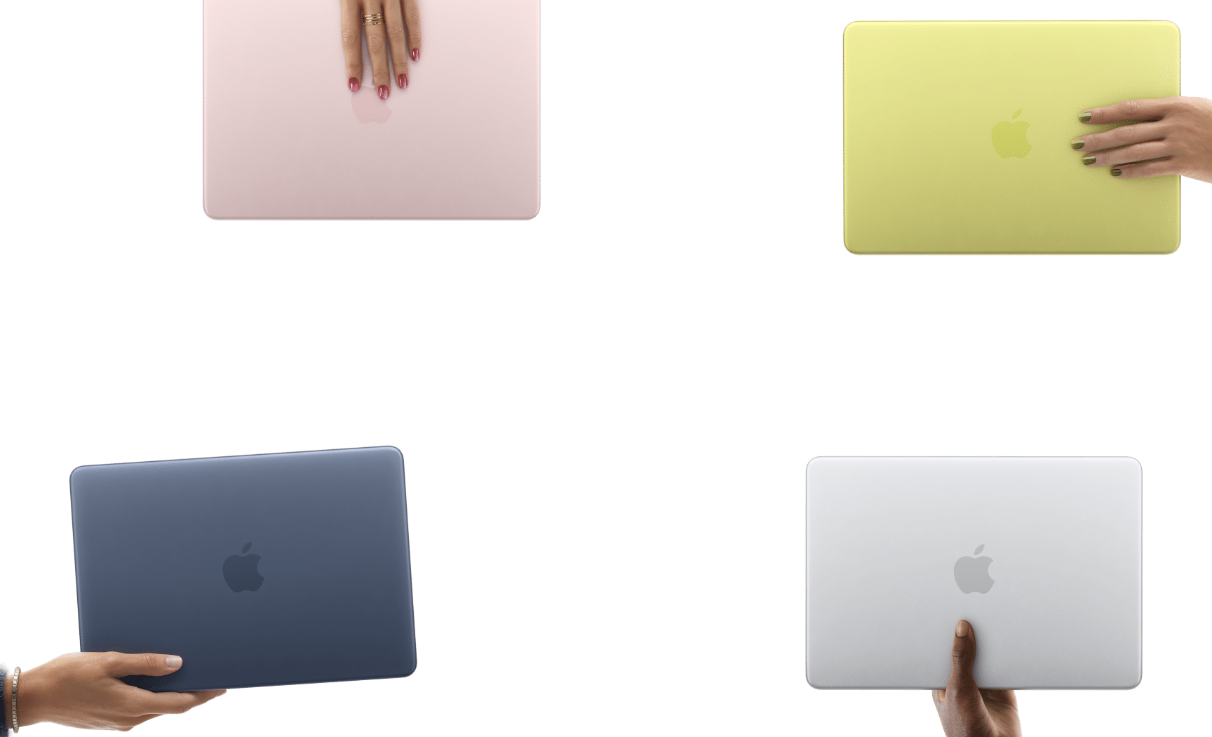 Four colourful MacBook laptops held by hands against a clean background.