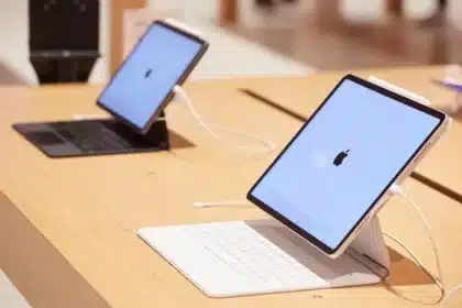 Two iPads on display stands connected to keyboards on a wooden table.