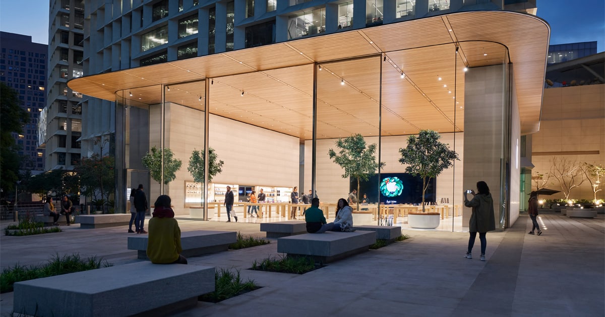 Modern Apple Store with glass walls and people outside at night.