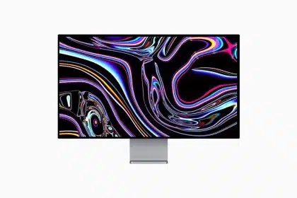 Apple Studio Display showing colourful abstract wallpaper on a slim monitor stand.