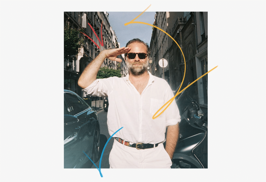 Man wearing sunglasses saluting on a city street with colourful graphic lines.