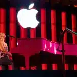 Alicia Keys performing at a pink piano under a glowing Apple logo.