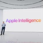Apple executive presenting &ldquo;Apple Intelligence&rdquo; on a large screen in a modern auditorium.