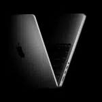 Apple MacBook partially open in a dark, minimal setting.