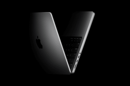 Apple MacBook partially open in a dark, minimal setting.