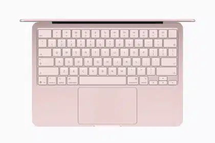Top view of a pink MacBook Neo laptop with keyboard and trackpad visible.