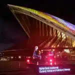 Sydney Opera House lit with colourful digital art during Apple event.