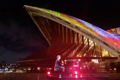 Sydney Opera House lit with colourful digital art during Apple event.