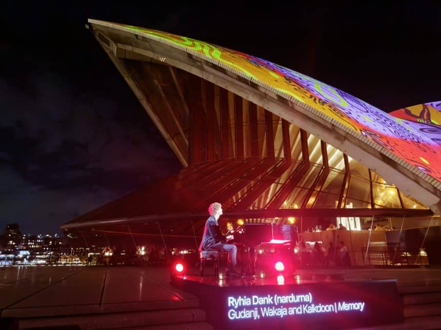 Sydney Opera House lit with colourful digital art during Apple event.