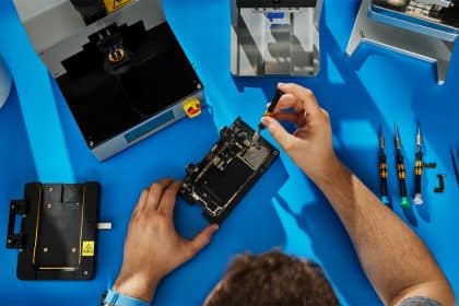 Person repairing a smartphone with tools on a workbench.
