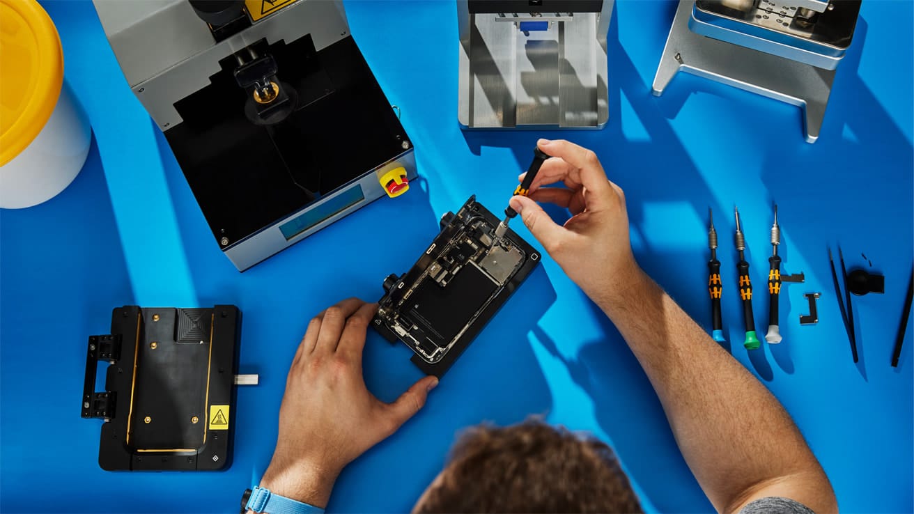 Person repairing a smartphone with tools on a workbench.