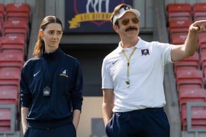 Ted Lasso coaching with a woman on a football field.