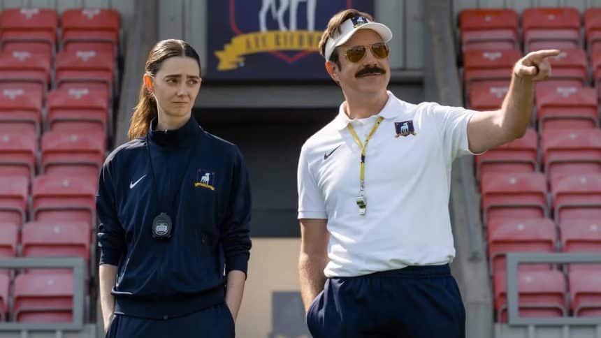 Ted Lasso coaching with a woman on a football field.