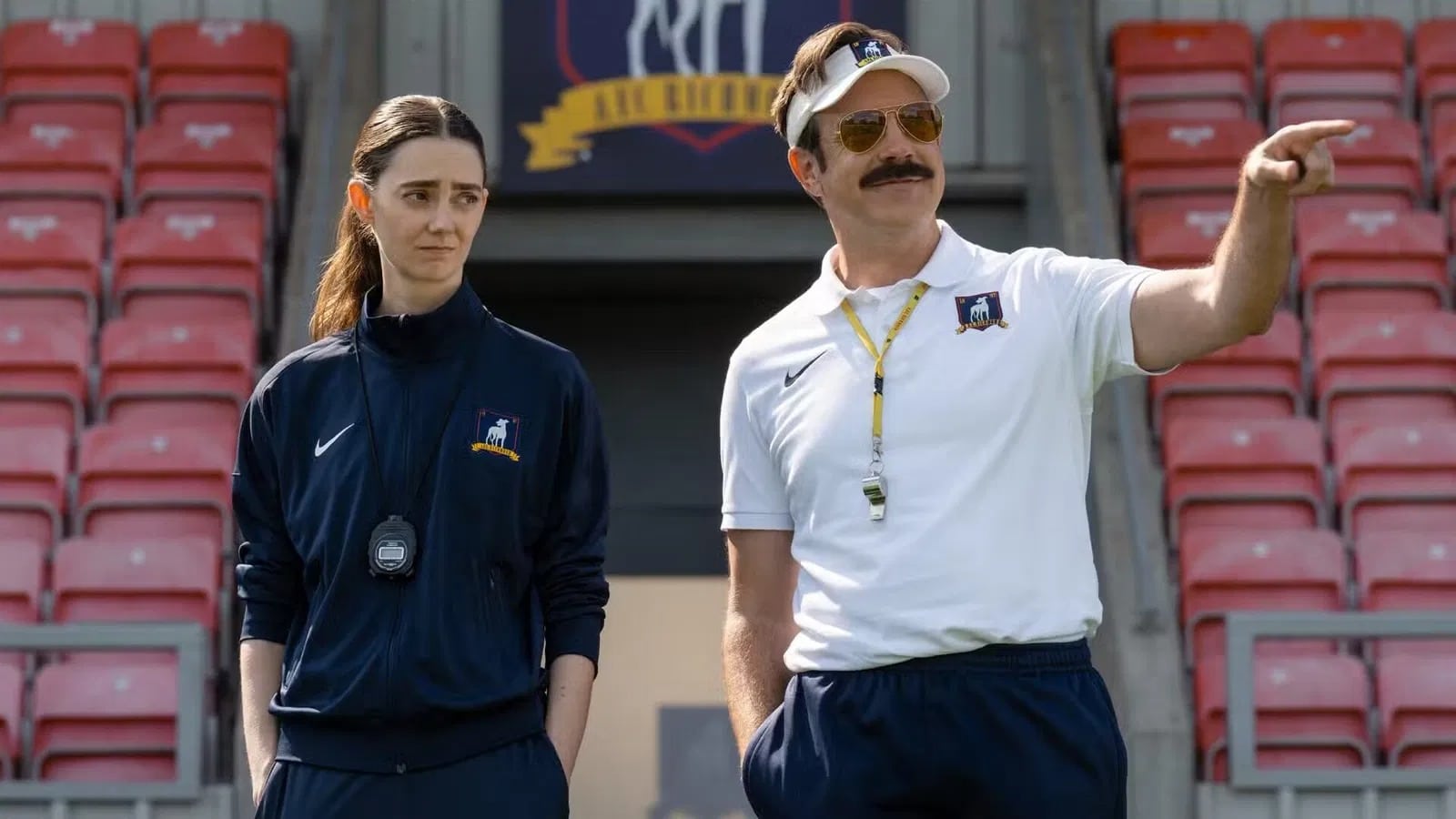 Ted Lasso coaching with a woman on a football field.