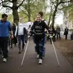 Woman using crutches walking in a charity event with a crowd.