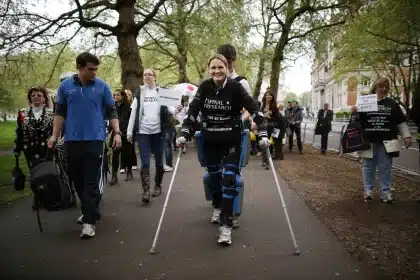 Woman using crutches walking in a charity event with a crowd.