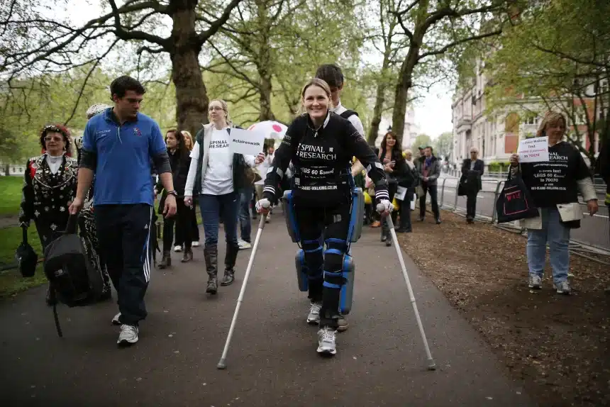 Woman using crutches walking in a charity event with a crowd.