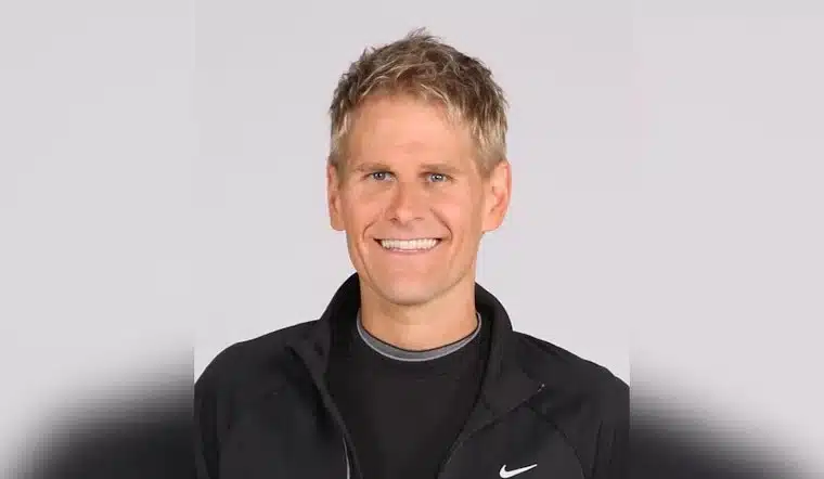Smiling man in a black athletic jacket against a plain background.