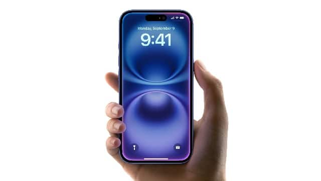 Hand holding an iPhone displaying the home screen.