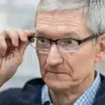 Man wearing glasses adjusting them with a focused expression.