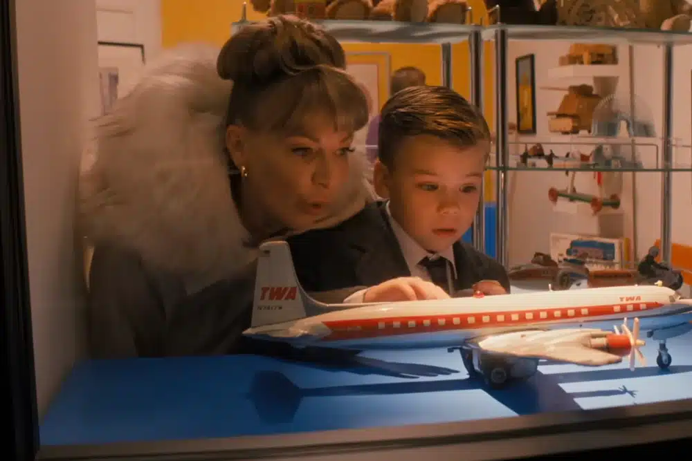 Woman and young boy looking at a vintage model airplane display.