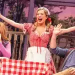 Actors performing a lively musical scene on a colourful stage.