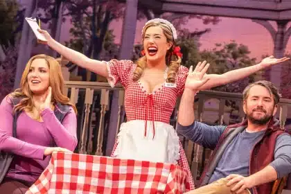 Actors performing a lively musical scene on a colourful stage.