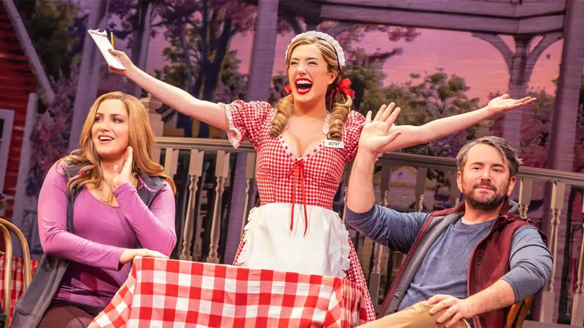 Actors performing a lively musical scene on a colourful stage.