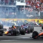 Formula 1 cars racing on track with a packed crowd in the background.