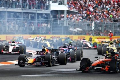 Formula 1 cars racing on track with a packed crowd in the background.