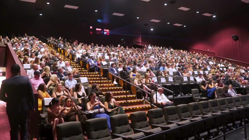 Large audience seated inside a modern movie theater auditorium.