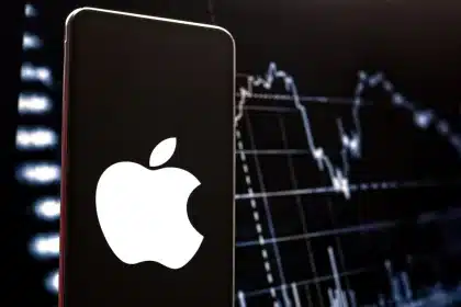 Apple logo on smartphone with stock market chart background.