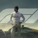 Race driver standing beside Formula 1 car in movie scene.