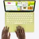 Hands using a green MacBook laptop viewed from above.