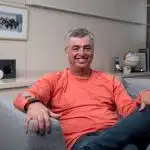 Eddy Cue smiling while seated on a couch in an office.