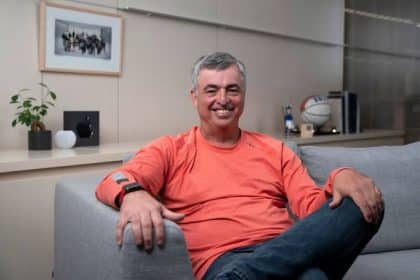 Eddy Cue smiling while seated on a couch in an office.