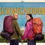 Promotional poster for Schmigadoon! featuring two hikers with backpacks standing in front of a colourful countryside backdrop.
