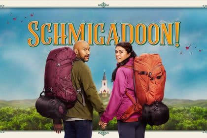 Promotional poster for Schmigadoon! featuring two hikers with backpacks standing in front of a colourful countryside backdrop.