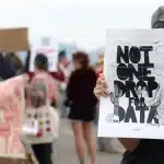 Person holding a protest sign reading &ldquo;Not One Drop for Data&rdquo; during a public demonstration.