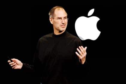 Steve Jobs presenting on stage with an Apple logo displayed behind him.