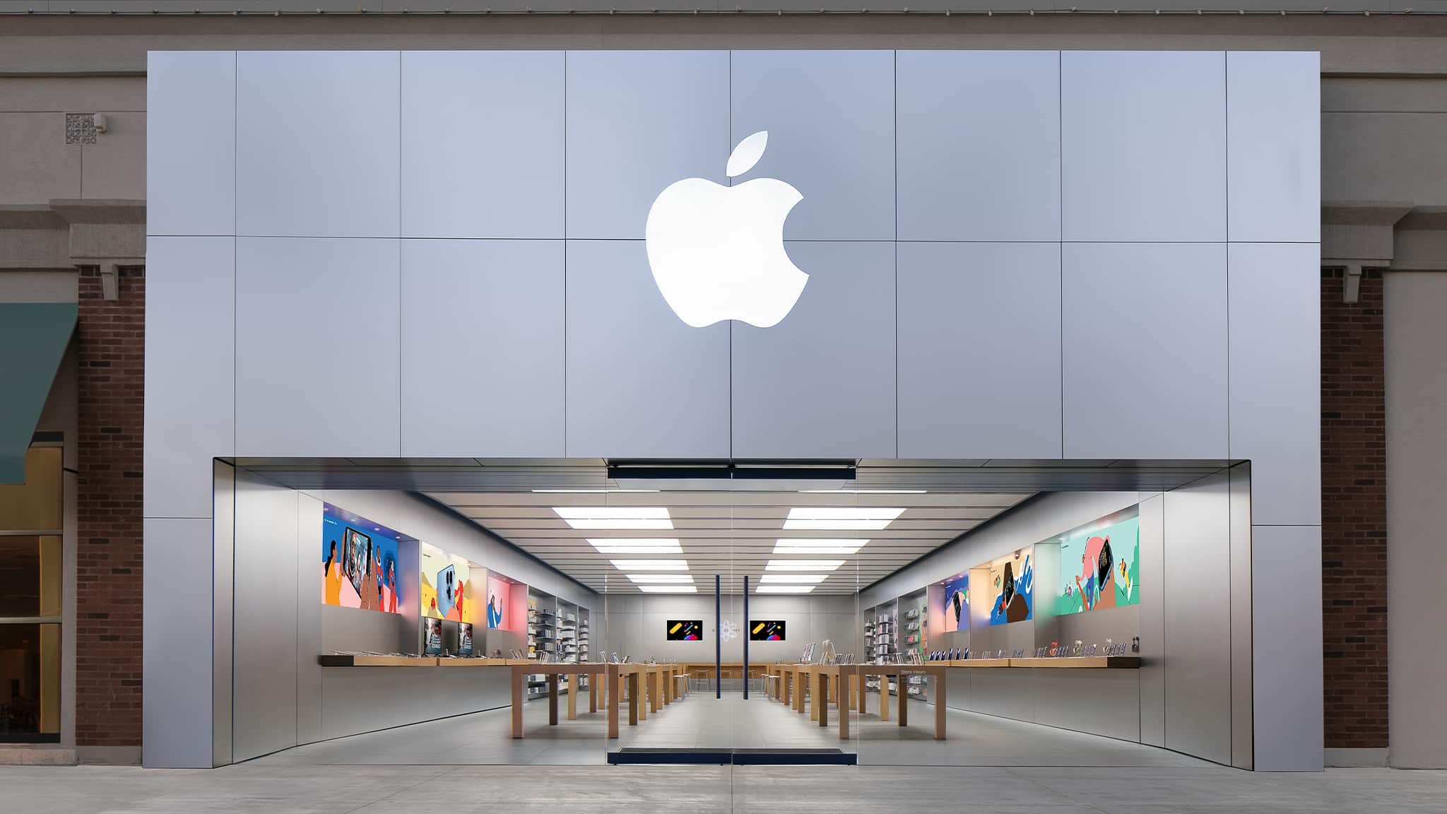 Apple Store entrance with a large illuminated Apple logo above the storefront.
