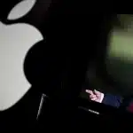 Apple logo beside a screen displaying U.S. President Donald Trump.