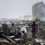 People stand among collapsed buildings and debris after a devastating earthquake in Venezuela.