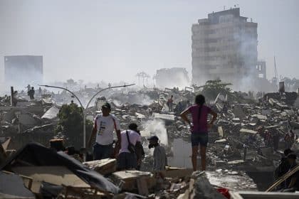 People stand among collapsed buildings and debris after a devastating earthquake in Venezuela.
