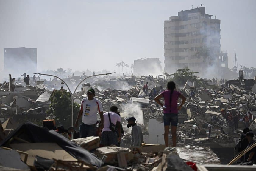 People stand among collapsed buildings and debris after a devastating earthquake in Venezuela.