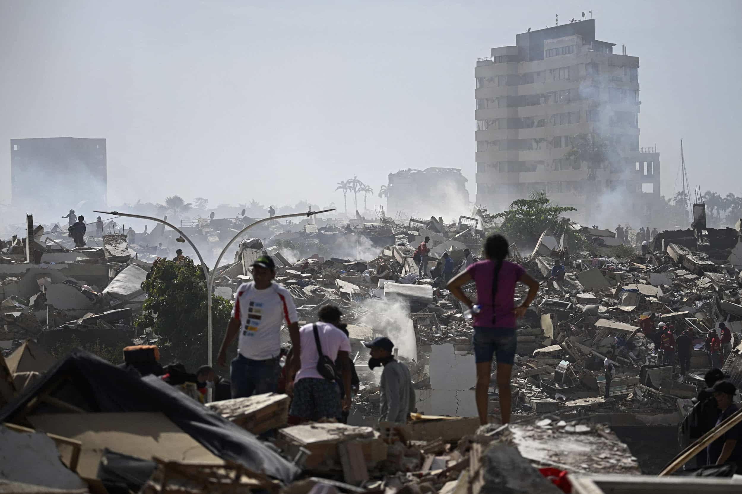 People stand among collapsed buildings and debris after a devastating earthquake in Venezuela.
