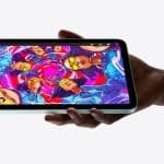 Person holding an iPad mini displaying colourful digital artwork.